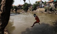 Mereka bermain, ayunan dari tali yang diikat di ranting pohon di pinggir sungai Ciliwung.