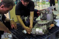 Dua teknisi melakukan pengecekan dan perbaikan mesin karburasi pesawat.