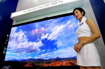 Seorang wanita siap menyambut pengunjung yang ingin melihat teknologi televisi terbaru.