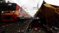 Kereta Commuter Line melintas di samping tenda darurat yang didirikan pengungsi korban banjir di atas rel di Kawasan Pesing Kedoya Utara, Jakarta Barat.