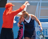 Dominika Cibulkova dibantu seorang ball boy mengalungkan handuk berisi es untuk mendinginkan leher belakangnya. (AFP)