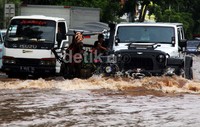 Delman melintas diantara sejumlah mobil di jalanan yang terendam banjir.