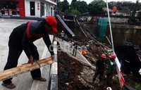 Petugas SPBU berusaha menopang, badan jalan yang tidak ikut amblas.