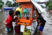 Pedagang bakso terlihat tetap menjajakan dagangannya meski di tengah banjir.