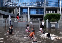 Anak-anak bermain di genangan banjir yang merendam jalan di depan kampus Universitas Tarumanegara.