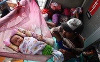 Seorang warga menunggui bayinya yang tertidur di tempat pengungsian di Halte TransJakarta.