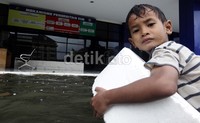     Seorang anak bermain air di depan kantor Satuan Penyelenggara Administrasi Surat Izin Mengemudi (Satpas SIM).