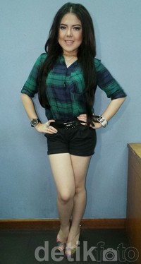 Tina Toonita bergaya kasual dibalut kemeja kotak-kotak hijau-biru dan hot pants hitam serta sepatu dengan motif bunga.