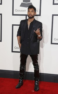 Miguel berpose di depan kamera mengenakan kemeja hitam dengan luaran blazer dipadu dengan celana kulit dari Saint Laurent. REUTERS/Danny Moloshok.     