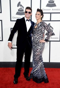 Berfoto bersama sang istri, Robin Thicke tampil mengenakan setelan tuxedo berwarna navy blue dari Giorgio Armani dipadu dengan kacamata hitam. Jason Merritt/Getty Images/AFP.