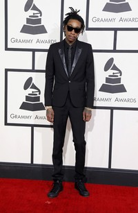 Wiz Khalifa mengenakan setelan tuxedo dari Saint Laurent dipadu dengan dasi hitam, kacamata hitam dan aksesori emas. REUTERS/Danny Moloshok.