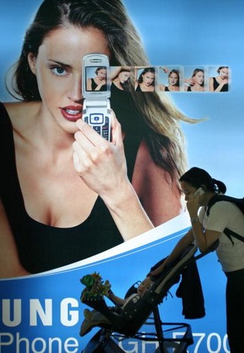 Seorang ibu melintas di depan iklan ponsel Samsung di sebuah mall di Jakarta pada Maret 2004.