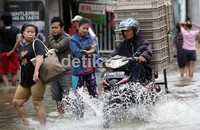 Pengendara sepeda motor menerobos banjir.