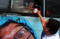 Seorang penumpang bus menerima stiker dari aktivis KIPP.