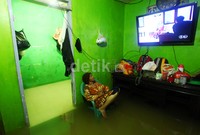 Terlihat seorang nenek tengah asik menonton acara televisi meski rumahnya terendam banjir.     