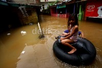 Warga memanfaatkan ban untuk menyeberangi banjir menuju tempat pengungsian.