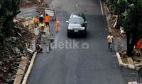 Aspal jalan telah mulus, hanya tinggal pembatas jalan yang belum semuanya terpasang.