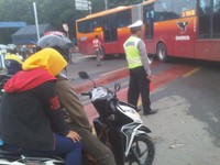 Pembonceng motor ini berusaha ngumpetin kepalanya karena tidak pakai helm. (Foto Ari Wibowo)