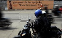     Pengendara motor melintas di samping mural berisi syair puisi aktivis Wiji Thukul.