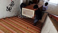 Empat orang warga membawa perabotan melalui tangga rusun.