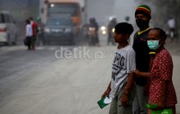 Tiga orang warga beraktivitas di bawah kepulan abu Kelud.