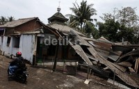 Seorang pengendara sepeda motor melintas di depan musala yang ambruk.