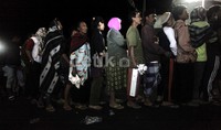 Warga mengante dengan memakai jaket dan sarung untuk menghalau hawa dingin.