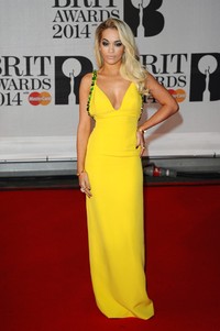 Tampil mengenakan gaun berwarna kuning dari Prada, Rita Ora tampil berseri-seri. Anthony Harvey/Getty Images.