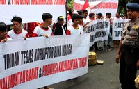 Massa membentangkan poster dan spanduk di depan kantor Kementerian Pekerjaan Umum, Jakarta.