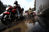 Para pengendara menghindari lubang yang menganga.