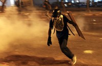 Salah seorang demonstran menghindari gas air mata dari aparat kepolisian. (REUTERS/Carlos Garcia Rawllins).