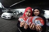 Dua orang petugas menunjukkan stiker saat sosialisasi Pemilu di kawasan Slipi, Jakarta Barat.