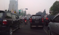 Para pengendara baik motor maupun mobil menembus kabut asap yang menyelimuti Pekanbaru.