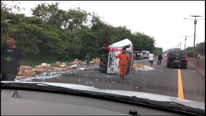 Mobil Boks Terguling di Tol Cikampek, Muatan Berserakan