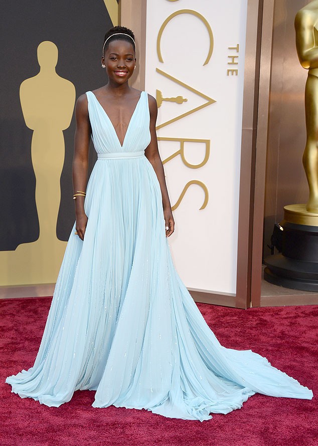 Aktris 12 Years a Slave, Lupita Nyongo tampil menawan dalam balutan gaun biru muda ala dewi Yunani dari Prada, di Oscar pertamanya ini. Taburan kilapan di sepanjang rok yang menyapu lantai membuat tampilan gaun semakin glamour saja. Headband, anting tempel serta gelang bernuansa emas ditambahkan, tampak harmonis dengan keseluruhan tampilan.