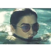 Ternyata ada seorang wanita cantik yang sedang berenang sambil mengenakan kacamata frame bulat besar berwarna kemerahan.