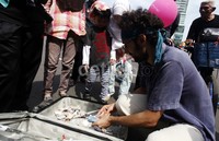 Para pengunjung di Bundaran HI sedang melihat Ram yang sedang menghitung uang.     