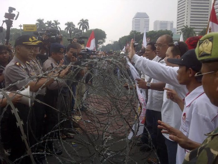 Pria Berkemeja Putih Tenangkan Massa Prabowo yang berseragam Loreng