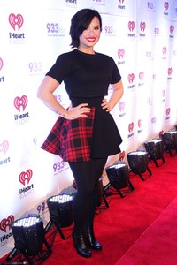 Demi Lovato tampil lewat busana serba hitam dengan detail motif kotak-kotak merah pada roknya. John Parra/Getty Images/detikFoto.