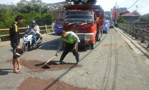 2 Polisi ini Tambal Lubang Jalan, Warga Sumbang Kerikil dan Pasir