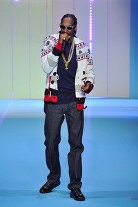Snoop Dog tampil kenakan t-shirt biru dengan luaran cardigan multi warna dipadu celana jeans dan tentu saja kacamata hitam. Kristy Sparow/Getty Images/detikFoto.