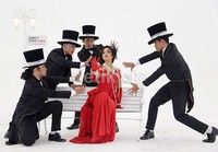 Fairuz yang mengenakan gaun merah menyala dikelilingi empat pria bertuxedo.