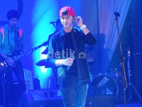 Ia tampil santai dengan kemeja, kaus dan celana serba hitam serta topi merah.