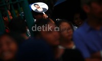 Seorang calon penonton mengacungkan foto Zayn Malik selagi antre tukar tiket.