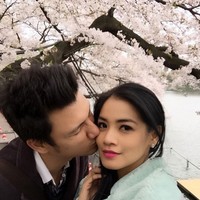 Tian mengecup mesra pipi sang istri di bawah pohon sakura. (Instagram/Titi Kamal)
