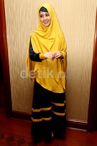 Risty dibalut busana bernuansa hitam dan kuning.