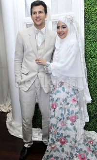 Risty tampak cantik mengenakan gaun bunga-bunga yang dipadukan dengan hijab putih. Sedangkan sang suami nampak gagah dengan setelan jas berwarna krem. Pool/Noel/detikFoto.