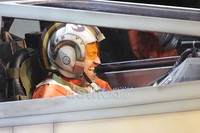 Penggemar yang mengenakan kostum seperti pilot X-Wing Fighter dan nampak bergembira mengendarai pesawatnya.