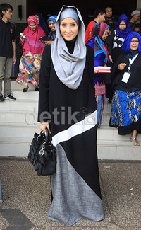 Ia tampil mengenakan gamis bernuansa hitam, putih dan abu-abu yang dipadu dengan hijab abu-abu. Pool/Akew/detikFoto.