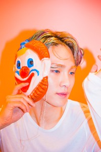 Key yang tampil dengan rambut warna-warni berpose sambil membawa topeng wajah badut dalam teaser fotonya. (SMTOWN)